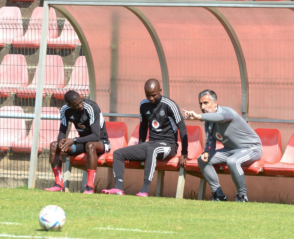 Orlando Pirates teammates with coach discussing.