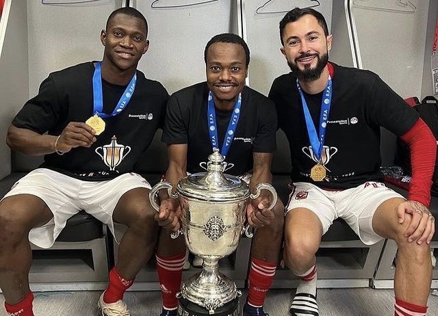 Percy Tau and teammates with trophy.